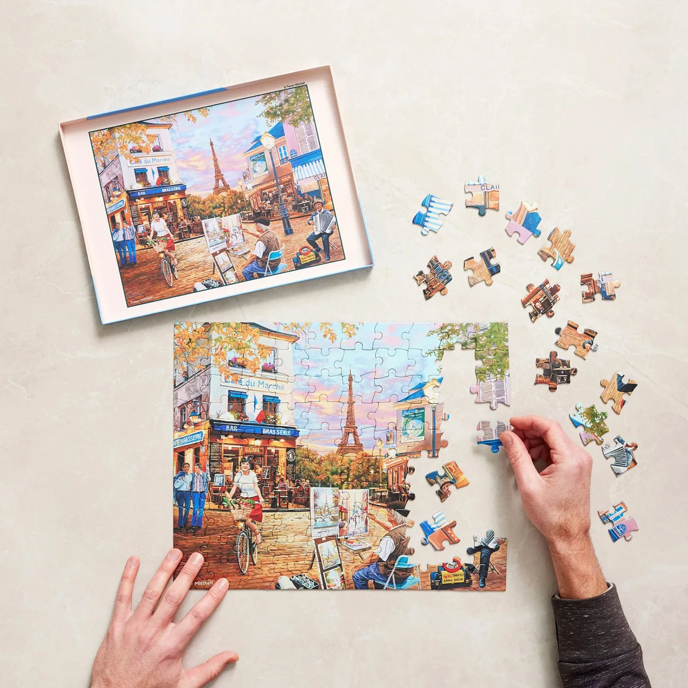 Hands assembling a Relish Paris scene jigsaw puzzle