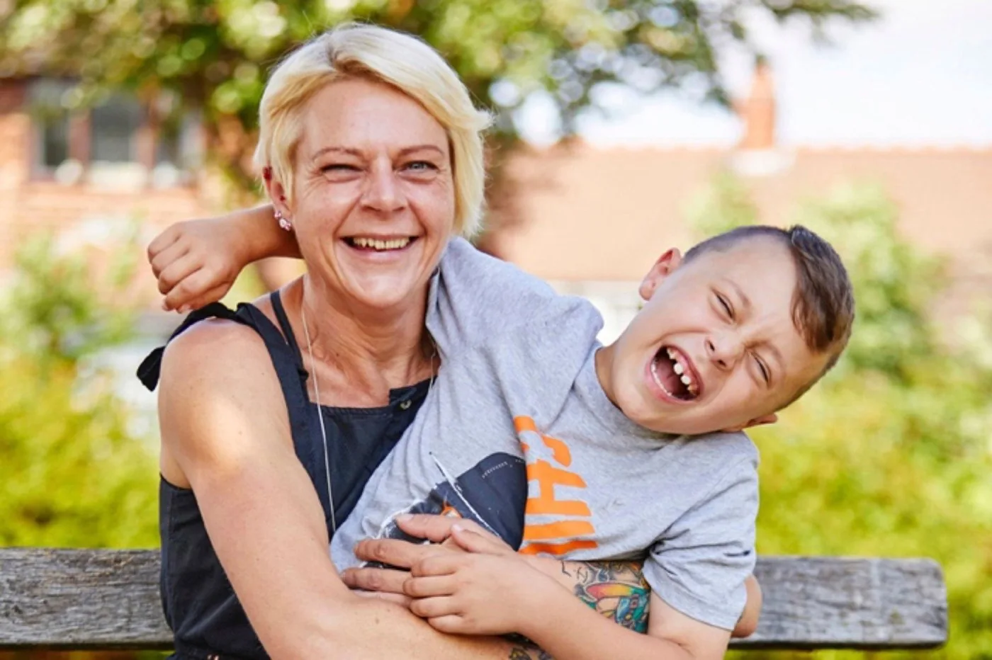 A parent and their laughing child sitting together outdoors